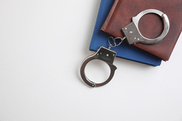 Flat lay composition with books and handcuffs on white background, space for text. Criminal law