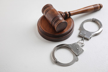Gavel and handcuffs on white table. Criminal law