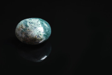 Beautiful moss agate gemstone on black background. Space for text