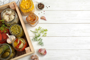 Jars with pickled vegetables on white wooden table, flat lay. Space for text