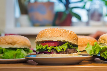 Three Homemade burger with tomato and beef patty, fresh toppings on whole grain artisan bun on kitchen table for dinner