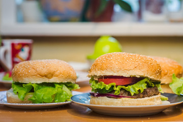 Two Homemade burger with tomato and beef patty, fresh toppings on whole grain artisan bun on kitchen table for dinner