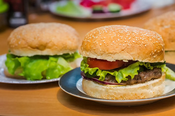 Two Homemade burger with tomato and beef patty, fresh toppings on whole grain artisan bun on kitchen table for dinner