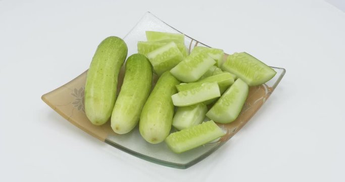Cucumber Sliced on plate rotating on white background.