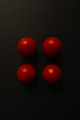 top view of four cherry tomatoes on a black background