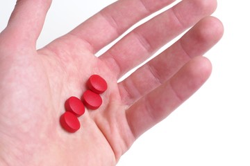 Medical treatment, prescription dose concept. Hand holding red pills on white background.