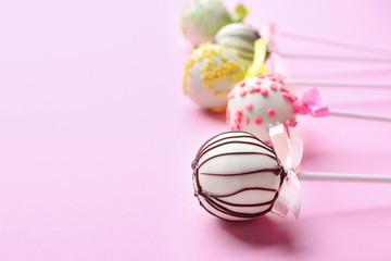 Fototapeta na wymiar Different tasty cake pops on light pink background. Space for text