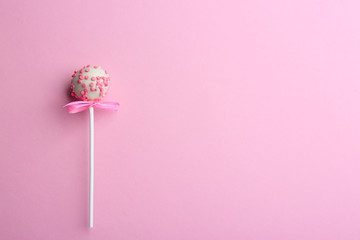 Tasty cake pop with bow on light pink background, top view. Space for text