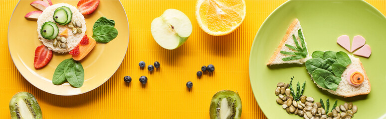 top view of plates with fancy animals made of food on colorful orange background, panoramic shot