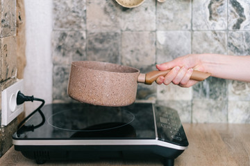 Woman putting pan on small electric stove
