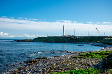 A view to lighthouse Girdle Ness from a rocky pebble beach near it, Aberdeen, Scotland