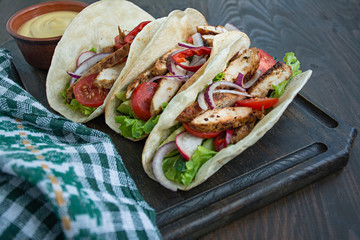 Mexican dish.Wrapped burrito with chicken and vegetables close-up on a wooden background. Space for text.