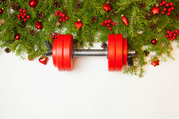 Christmas or New Year on a white background. Composition with dumbbells, gift, red glass balls, fir tree branches for healthy lifestyle and sport
