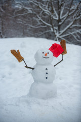 Snowmen - gift presents concept. Merry Christmas and happy new year greeting card. Festive Art Greeting Card. Cute snowman in hat and scarf on snowy field with surprise Christmas gift.