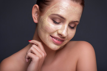 Beautiful young european woman apply clay mask on her face. beauty spa concept