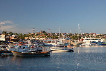 Small fishing boats and yacht anchored in the harbor. It was filmed during the sunset.