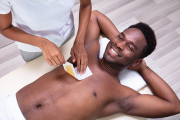 Person Hands Waxing Man's Chest