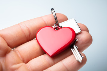 Human Hand Holding Red Heart Shape Key Chain With Key