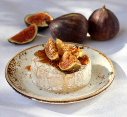 Baked Camembert cheese with fig jam and fresh figs, hard sunlight, deep shadow. sunny weather....