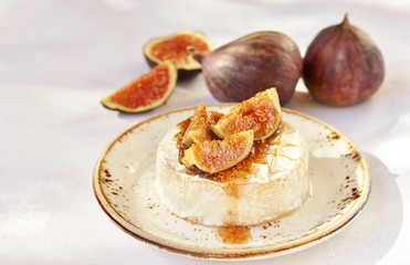 Baked Camembert cheese with fig jam and fresh figs, hard sunlight, deep shadow. sunny weather. fashion light, copy space