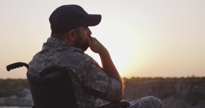 Soldier sitting in a wheelchair on a meadow
