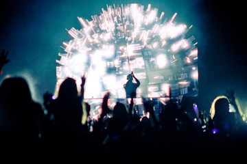 DJ on stage clapping with crowd in the foreground