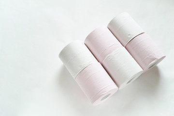 白バックの右寄りに3ロールずつ2列で寝かせてある白とピンクの新品のトイレットペーパー