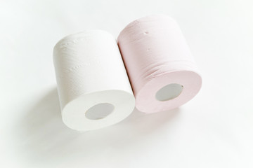 白バックの中央に2ロール転がるように置いてある白とピンクの新品のトイレットペーパー
