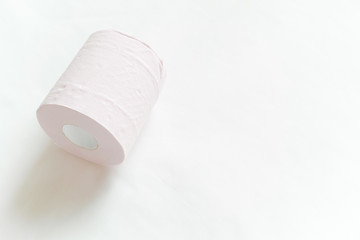 白バックの左寄りに1ロール転がるように置いてあるピンクの新品のトイレットペーパー