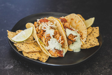 Mexican fresh chicken tacos with cabbage, cheese and cilantro cream sauce in a flour tortilla with multigrain corn tortilla chips