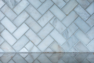 white and gray herringbone italian marble tile in a kitchen as a backsplash with the reflection on...