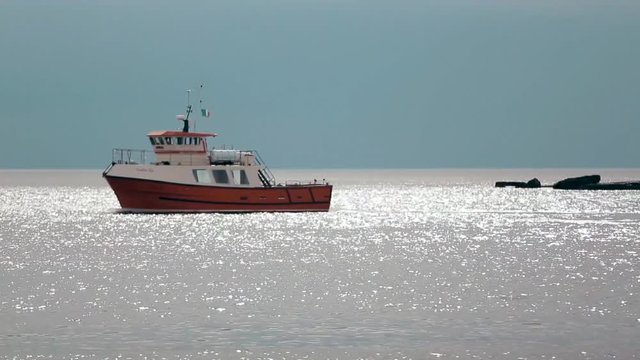 Fishing trawler with the Irish flag floating in the calm waters of the Atlantic Ocean. Commercial fishing boat goes to the open sea in the morning.