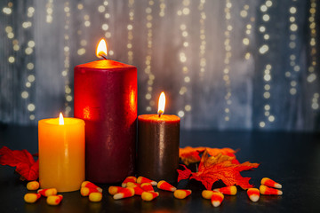 set of three autumn colored candles burning in the fall glowing from the candlelight
