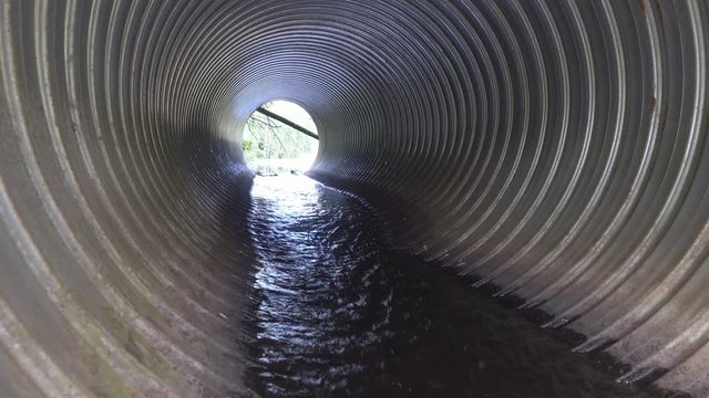 Big culvert under the highway. On the water in the pipe and shoots