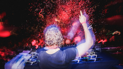 long haired DJ puts his finger up in front of crowd with confetti cannons