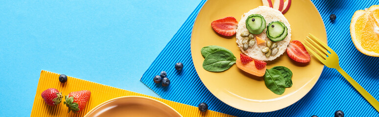 top view of plate with fancy animal made of food on blue and yellow background, panoramic shot
