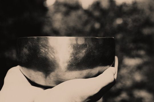 Black and white photo of acoustic healing singing bowl in female palm. Bowl for meditation and sound balance of concentration in female hands.