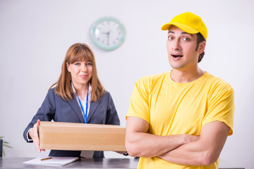 Young male courier delivering box to hotel's reception