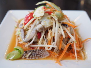 Som tum, Papaya salad with shrimp and raw crab is spicy Thai food. som tam in a white plate delicious food in Thailand