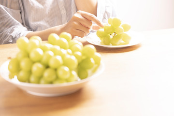 ぶどう（シャインマスカット）を食べる女性