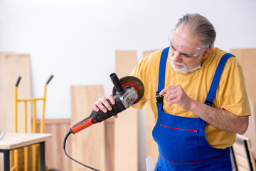 Old male carpenter working in workshop