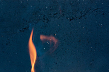 Fototapeta na wymiar Flames in motion on a dark grainy texture of the metal