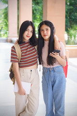 Naklejka premium Asian university students chating, talking in university campus. Female university students talking, studying and exchanging together in university campus. Education and life style concept.