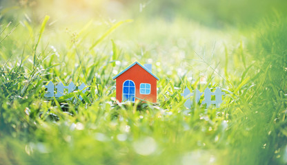 Fototapeta na wymiar Orange house model on green grass.