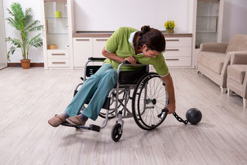 Young male invalid in wheel-chair suffering at home