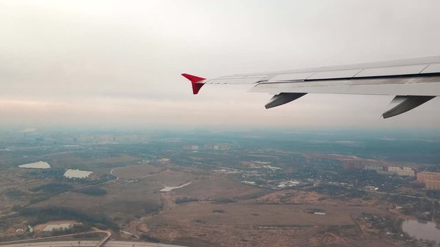 View of the wing from the window of a passenger plane taking off over the city of Moscow