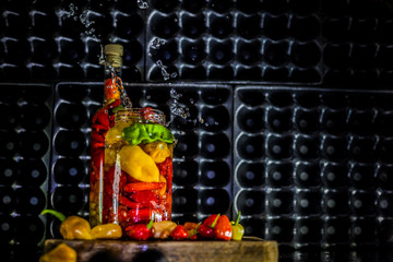 Fototapeta na wymiar Peppers in motion ,colorful composition of peppers, chili sauce and preserved preserves in bottle and pot.