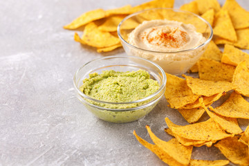 Hummus and guacamole with nachos on a gray background. Selective focus. Copy space
