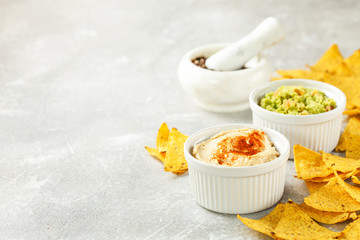 Hummus and guacamole with nachos on a gray background. Selective focus. Copy space
