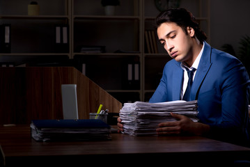Young male employee working night in the office